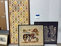 Three framed batik artworks leaning against a wall showing different designs and sizes.
