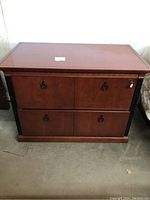Front view of wooden credenza showing two lateral file drawers, metal ring pull handles, and working key in lock on right drawer