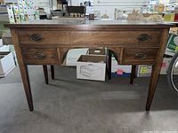 Full view of Biggs wooden dressing table with three drawers and open kneehole space beneath center drawer.