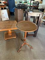 View of two wooden end tables including the shorter Ethan Allen square table and the taller round colonial style candle stand.