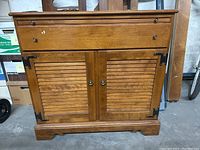 Front view of Ethan Allen buffet cabinet showing shutter style doors with metal corner accents and top drawer with knobs.