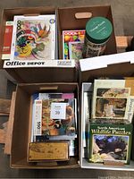 Multiple boxes full of jigsaw puzzles showing puzzle boxes stacked and organized, identifiable puzzle covers visible.