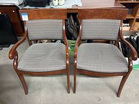 Pair of conference chairs front view showing wood arms, legs, and patterned seat and back upholstery.