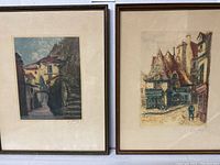 Pair of framed French prints showing two village scenes side by side, in simple frames.