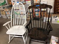Front view showing both rocking chairs; white chair with paint wear, brown chair with minor seat damage.