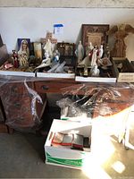 Full view of the religious items spread over two cardboard trays on a wooden surface, showing figurines, Bibles, candles, and other items.