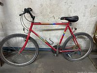 Red Specialized Hard Rock men's hardtail mountain bike from side view showing frame, tires, seat and handlebars.