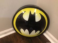 Front view of the round Batman globe light showing the black Batman symbol on a yellow and white background.