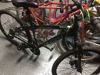 Side view of black Huffy Night Hawk men's mountain bike showing frame with blue and green accents, tires, pedals, and chain.