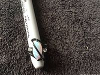 Front angle view of black ring with central opal stone and two clear side stones, on a measuring tool showing ring size.