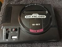 Front top view of the black Sega Genesis MK-16000 console showing the cartridge slot, power switch, reset button, and volume slider.