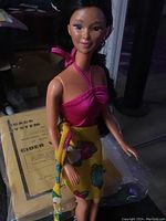 Vintage Mattel Barbie doll wearing pink halter top and yellow floral skirt, close-up showing upper body, face and outfit.