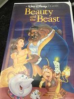 Photo of the original illustrated cover featuring characters Belle, Beast, and enchanted household items from Beauty and the Beast.
