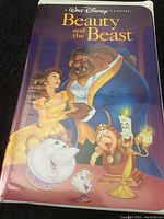 Front cover sleeve of the VHS tape showing animated characters from Beauty and the Beast including Belle, Beast, Mrs. Potts, Chip, Cogsworth, and Lumiere on a purple background.