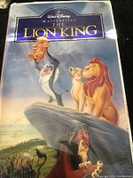 Front cover of The Lion King VHS tape with colorful character artwork showing iconic scene with Rafiki holding Simba, other lion characters, and Scar below the rock formation.