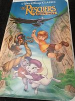 Front cover artwork of the VHS tape showing Disney's The Rescuers Down Under with animated characters hanging from ropes and flying in a canyon background.