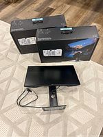 Two Dell UltraSharp 24 monitors shown with original boxes and one monitor with power cord attached, angled overhead view.