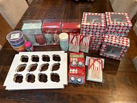 View of full assortment of baking cups, cupcake boxes, inserts, and sprinkle containers arranged on table