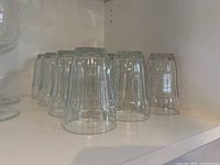 Clear drinking glasses arranged upside down on a shelf, showing the uniform size and shape of the glasses.