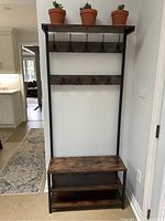 Front view of full hall tree showing top shelf, hook panels, bench and lower shelves