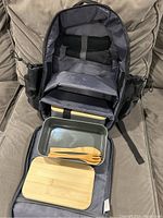 Photo of the open black nylon picnic backpack showing the compartments, two bento box containers and napkins inside.