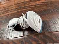 Conair portable handheld fabric steamer placed on wood surface; front and side views showing steam head and water tank.