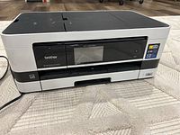 Front view of Brother Business Smart Series printer and scanner unit with closed scanner lid, showing front panel and power cord.