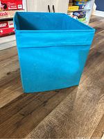 Single turquoise storage cube sitting on the floor, showing clean fabric and reinforced edges.