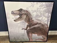 Front view of the framed T-Rex canvas wall art on a dark blue wall.