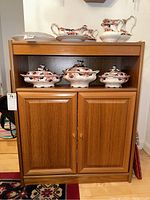 Front view of wood cabinet showing two paneled storage doors and decorative items on top (not included).
