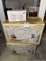 Two boxed Gibson Napa Harvest 32-piece dinnerware sets stacked with a boxed porcelain creamer and sugar bowl set on top.