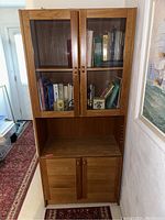 Full view of the Danish modern bookcase showing both upper glass doors filled with books and lower wooden doors, straight front view.