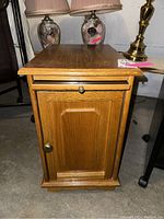 Front view of wooden end table showing pull-out tray, storage door with knob, and flat top surface.