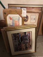 Stack of framed prints and photo frame showing various sizes and gold-toned frames