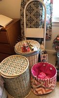Image of metal step stool, wicker baskets, and pink fabric basket on floor near wooden furniture.