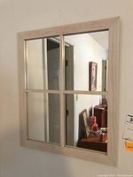Full view of the rectangular window style wood framed mirror hanging on a wall.
