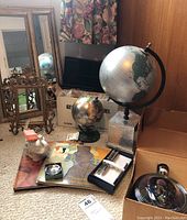 Wide shot of lot including metal frames, two globes (one boxed), Eisenhower bottle, framed mirrors, desk accessories.