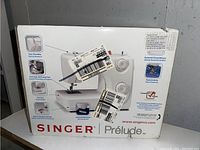 Front view of box showing Singer Prelude sewing machine features and branding.