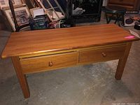 Front view of teak wood coffee table showing two drawers and wooden drawer knobs, highlighting surface and construction.
