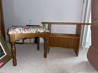 Side view of upholstered ottoman beside teak side table with magazine rack