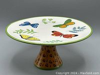 Side angled view of the ceramic cake stand showing the butterfly decorated plate and leopard print pedestal base.