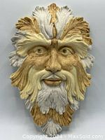 Front view of the Green Man ceramic plaque showing overall shape, colors, and details including foliage design and facial features.