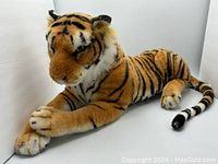 Front right diagonal view of the large sitting plush tiger showing orange fur with black stripes, white face and ears, and detailed eyes and nose.