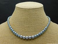 Full view of necklace draped on display bust against black background