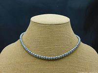Full view of 18 inch single strand necklace with silver/gray pearls displayed on a beige mannequin neck form.