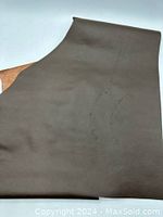 Photo showing the entire brown leather piece with visible scratches on the smooth side, illustrating condition and size.