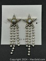 Front view of pair of rhinestone star tassel earrings on white card with brand KAENA GAI visible.