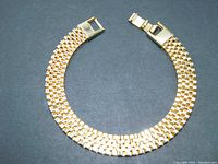 Top view of the five row gold tone Panther Link bracelet laid open showing the interlocking box pattern and fold-over clasp.