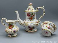 Full view of the coffee pot, creamer, and sugar bowl set showing floral pattern and gold trim.
