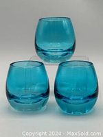 Three heavy blue glass candle holders with rounded shape, displayed on a white background.